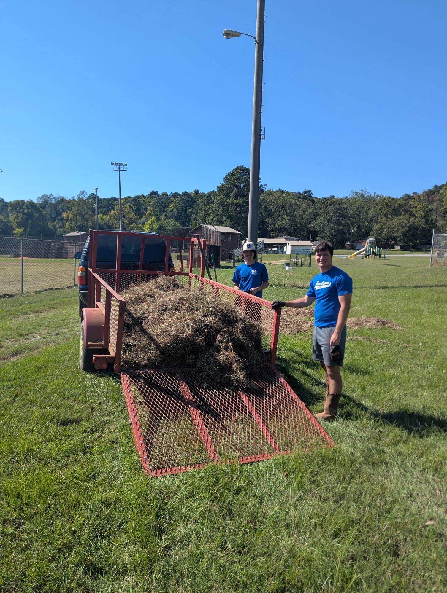 Drake Wade and Kent beside a trailer full of weeds removed from Tippy Field