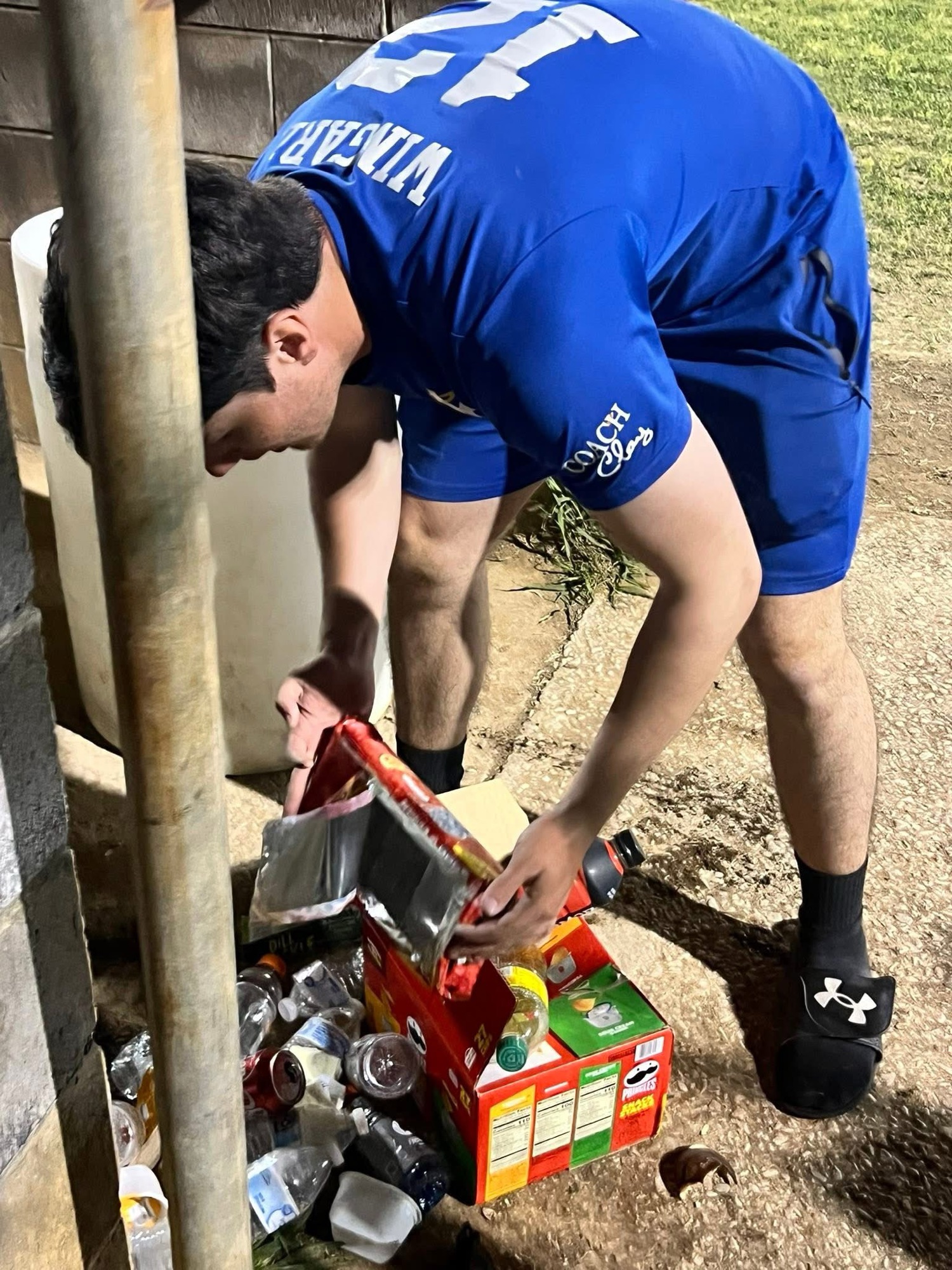 HC coach cleaning up discarded containers and trash around the baseball field